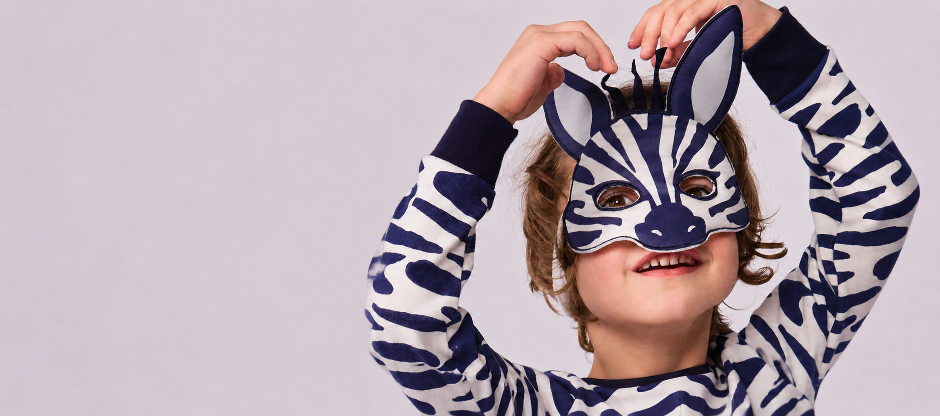 Child wearing zebra-print Petit Bateau nightwear and a zebra mask