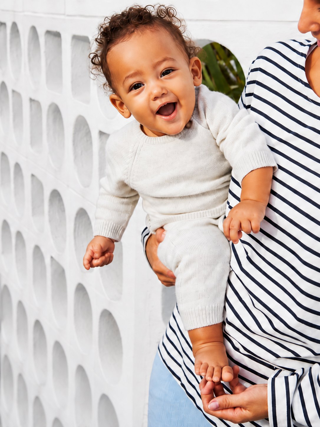Baby in Petit Bateau organic cotton knitwear held by their mother
